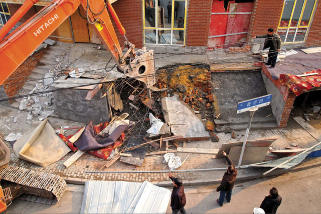 Three people give directions to a bulldozer driver demolishing an illegal structure, Shanghai, 29 January 2013. Photo: Remko Tanis